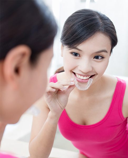 Smiling woman placing Invisalign tray