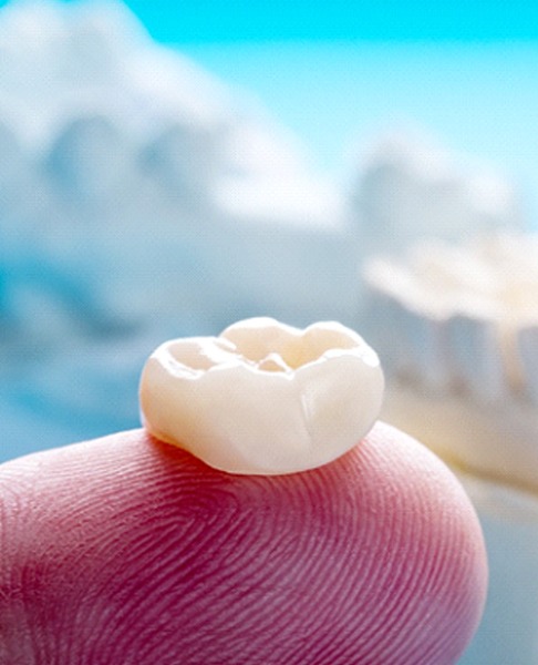 Closeup of dental crown in Collegeville on finger