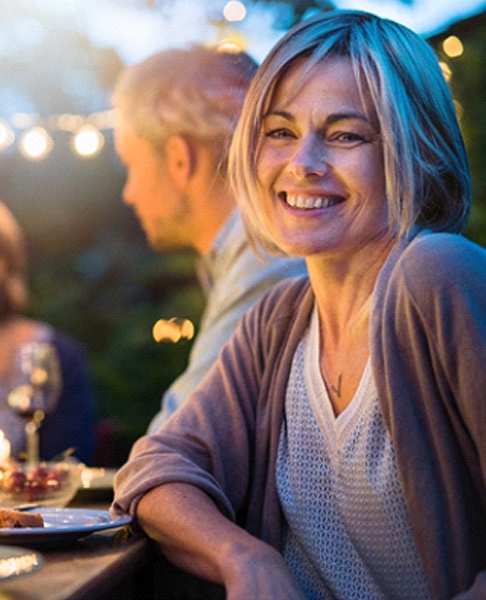 Woman with dental crowns in Collegeville smiling at dinner party