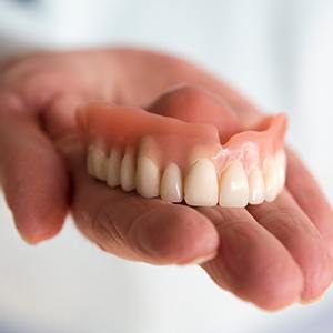 closeup of person holding dentures