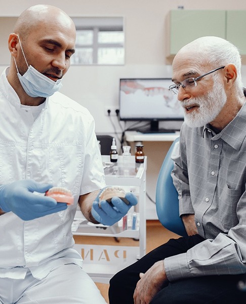 An older gentleman listens as his dentist explains whether he is eligible to receive dentures in Collegeville