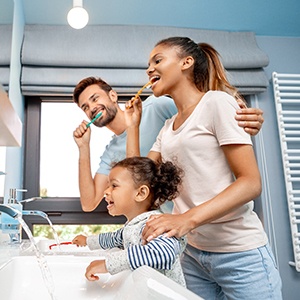 Family smiling while brushing their teeth together