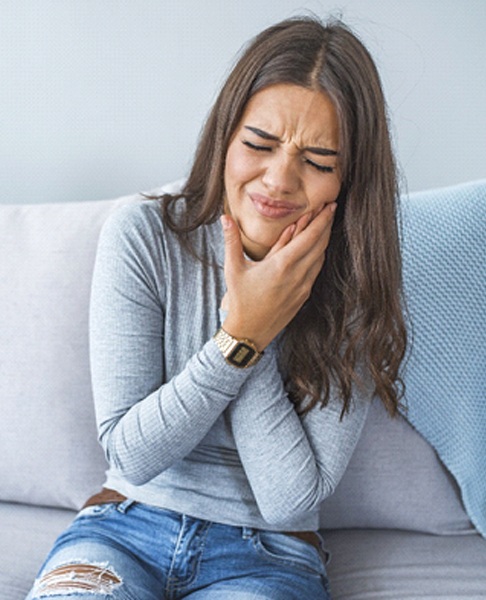 Woman on couch nursing a toothache