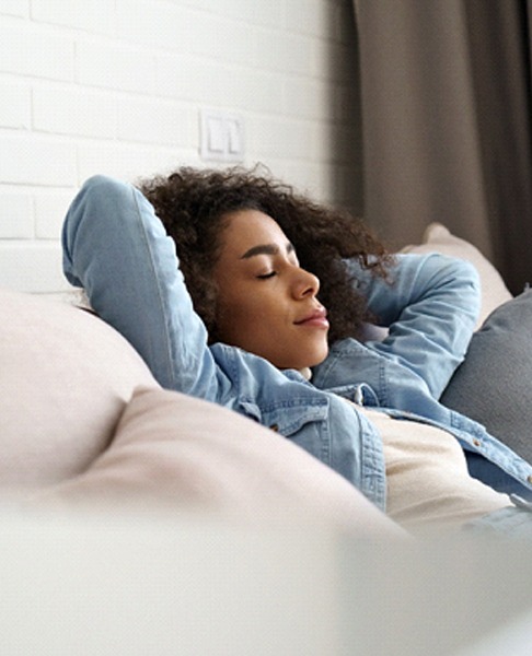 Woman resting on couch after tooth extraction in Collegeville, PA