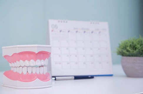 Dental model on desk next to calendar and pen