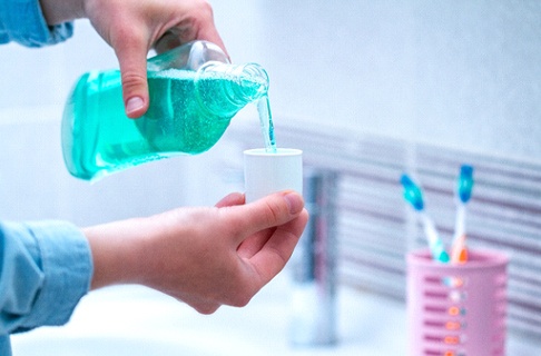Pouring green mouthwash as part of oral hygiene routine