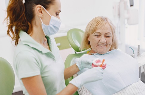 An older woman listens as her dental hygienist shows her how to take proper care of her dental implants in Collegeville