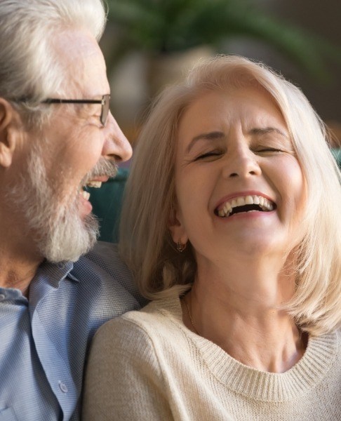 Man and woman laughing together after dental implant tooth replacement