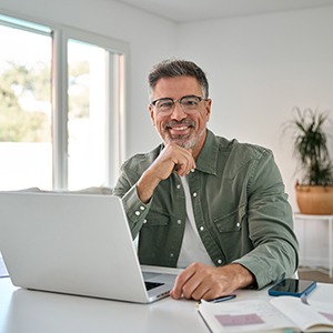 Man smiling while working on laptop at home