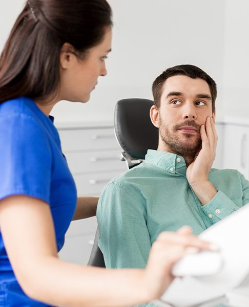 Man in need of root canal therapy holding jaw