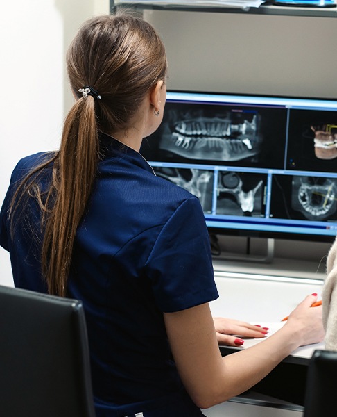 Dental team member looking at digital x-rays of teeth