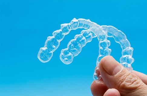 person holding two clear aligners 