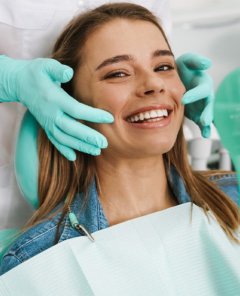 woman smiling while holding Invisalign aligner