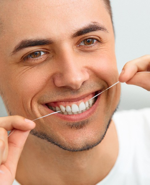 Closeup of man smiling while flossing his teeth