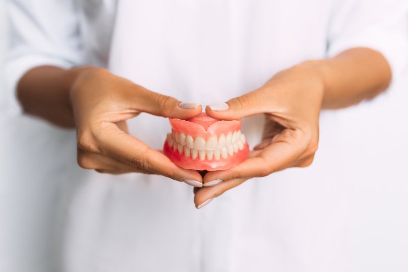 an up-close view of a dental professional holding a full set of dentures in their hands