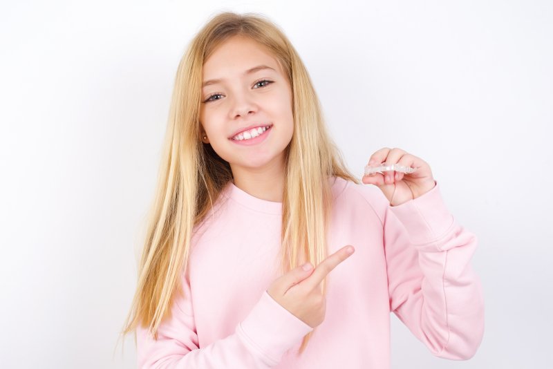 teenager smiling while holding Invisalign