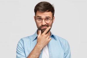 Man wondering about Invisalign in Collegeville on gray background