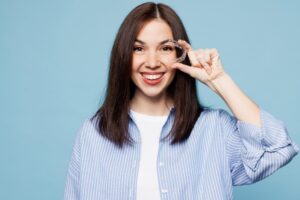 Woman smiling and holding clear aligner.